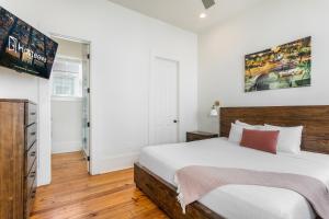 a bedroom with a large bed with white walls and wooden floors at Private 3BR on Carondelet by Hosteeva in New Orleans