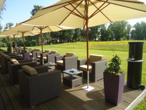 eine Reihe von Stühlen und ein Regenschirm auf einem Deck in der Unterkunft Spreewald Thermenhotel - Spreewald Therme GmbH in Burg