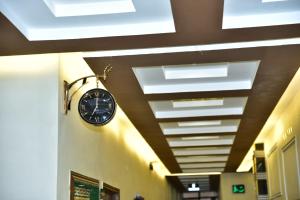 a clock hanging on a wall in a hallway at Kings Hotel in Sargodha