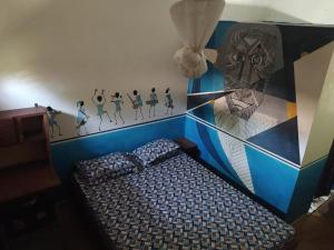 a bedroom with a bed with a painting on the wall at Chez Yaya, chambre bleue in Oussouye