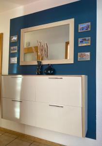 a white dresser with a mirror on a blue wall at Zentrale Ferienwohnung in Plettenberg in Plettenberg