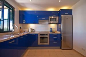 a kitchen with blue cabinets and a stainless steel refrigerator at Casa Palmeras, Punta Limones, Playa Blanca, Lanzarote in Playa Blanca