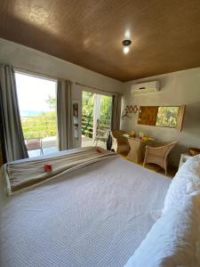 - une chambre avec un grand lit blanc et une vue dans l'établissement Maiga Pousada- Casa do Marcelino, à Fernando de Noronha