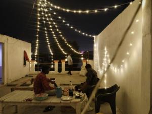 two men sitting at a picnic table under lights at Milestone Homestay Agra in Tājganj
