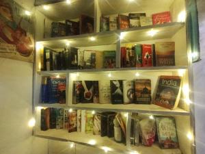 a book shelf filled with books on a wall with lights at Milestone Homestay Agra in Tājganj