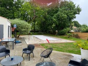 a patio with tables and chairs and a pool at Maison familiale LA ROCHELLE in LʼHoumeau