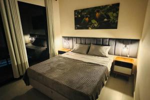 a bedroom with a bed and a painting on the wall at COC00N HOUSE - Vale do Capão in Palmeiras
