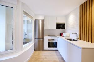 une cuisine avec des armoires blanches et un réfrigérateur en acier inoxydable dans l'établissement Clínica Universitaria y Hospitales by Clabao, à Pampelune