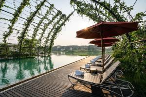 a row of chairs with an umbrella on a dock at THANN Wellness Destination in Phra Nakhon Si Ayutthaya