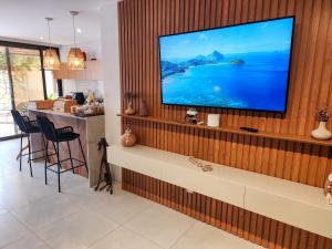 a living room with a television on a wooden wall at Kanui Casa Maré 107 in São Miguel dos Milagres +50 photos