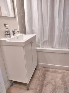 a white bathroom with a sink and a bath tub at Basement Waterloo Near 24-7 Restraints in Waterloo +38 photos
