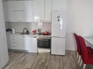 a white kitchen with white appliances and red chairs at At the Church in Ohrid