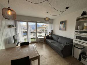 a living room with a couch and a table at Studio cabine rénové, 4 couchages, pied des pistes, parking, balcon sud - FR-1-297-160 in Auris