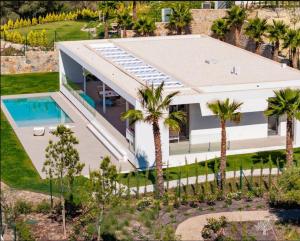 ein Luftblick auf ein Haus mit einem Pool und Palmen in der Unterkunft LIMA 18 , Las Colinas Golf, Orihuela costa in Orihuela + 31 Fotos