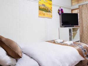 a bedroom with a white bed and a tv at 羊の宿地铁口徒步六分钟电车八分钟到梅田商圈 in Osaka