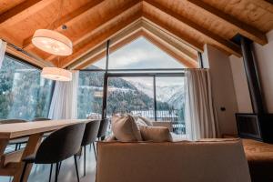 a living room with a table and chairs and a large window at DALANIA MOUNTAIN APARTMENTS in Ponte di Legno