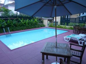 a pool with a bench and an umbrella and a table at Pousada Magister in Petrópolis