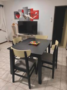 a black dining room table with chairs and a television at Espacio Seven Mendoza in Guaymallen
