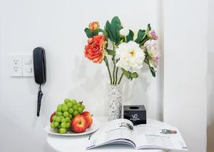 a table with a book and a vase of flowers and fruit at Le Vu Hotel in Ho Chi Minh City