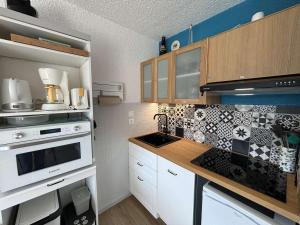 a kitchen with white cabinets and black and white tiles at Studio cabine rénové, 4 couchages, pied des pistes, parking, balcon sud - FR-1-297-160 in Auris