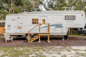 a white rv parked in a yard with a ramp at Shaanti Living Cozy Private Camper 2 in Melrose