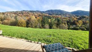 a chair on a deck with a view of a field at Appt Le Borgeal - rez de jardin, au calme in Les Villards-sur-Thônes