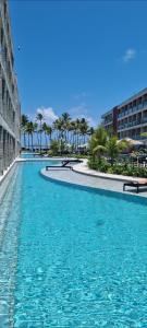 une piscine avec de l'eau bleue et des palmiers dans l'établissement Porto Alto, à Ipojuca