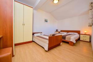 a bedroom with two beds and a closet at Apartman Ivka A1 in Petrcane