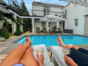 two people with their feet up on a chair next to a swimming pool at Le Petit Paris in Franschhoek