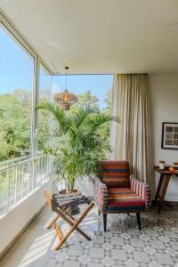 a living room with a chair and a plant on a balcony at Presidential Luxury Villa Anjuna with Private Pool and Dedicated Caretaker in Old Goa