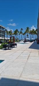 a boardwalk with tables and palm trees on the beach at Porto Alto in Ipojuca