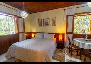 a bedroom with a bed and a table and a window at Chalés Caminho das Montanhas in Monte Verde
