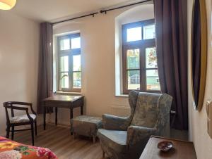 a living room with a chair and a table and windows at Vintage-Wohnung Silberstadt in Freiberg