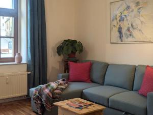 a living room with a blue couch and pink pillows at Vintage-Wohnung Silberstadt in Freiberg +5 photos