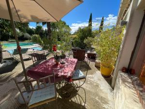 a table with chairs and an umbrella next to a pool at Mas de la Butte Blanche in Orgon
