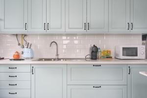 una cucina con mobili bianchi, un lavello e un microonde di VintageHouse a Campo Maior