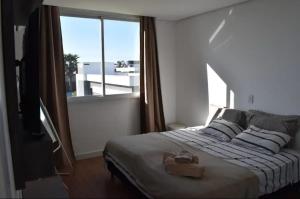 a bedroom with a bed and a large window at Aluguel de Temporada - Dubai Resort Residencial in Capão da Canoa