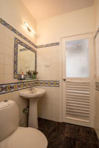 une salle de bain avec toilettes, lavabo et miroir dans l'établissement Vilas De Santa Ana at Costas Montage Benaulim, à Benaulim