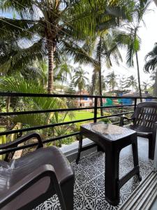 a patio with a table and chairs and palm trees at V R Holiday Home in Candolim