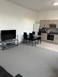 a living room with a table and chairs and a television at Barnsley Guesthouse in Barnsley