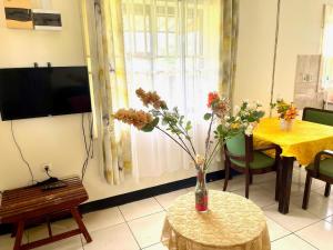 a living room with a vase of flowers on a table at 3 Bed House - Sleeps 6 - Garden - Parking - Wifi in Paramaribo