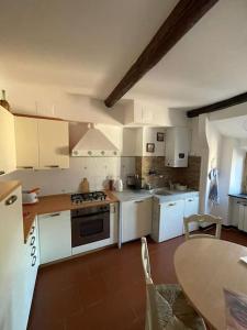 une cuisine avec des placards blancs et une table avec une table dans l'établissement I Monti sul Mare - appartamento a Genova Pegli, à Gênes