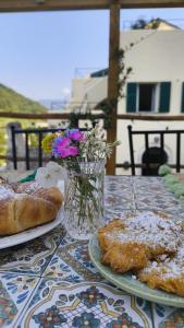 a table with two plates of pastries and a vase of flowers at Cà Eucalipto in Finale Ligure