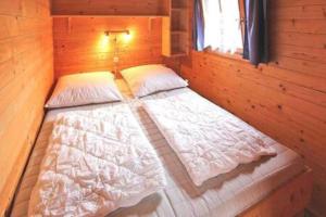 a bed in a wooden cabin with a window at Gemütliche Ferienhütte am See mit großem Garten in Rechlin