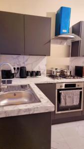 una cocina con fregadero y estufa en Mancunian Pride Villa, en Mánchester