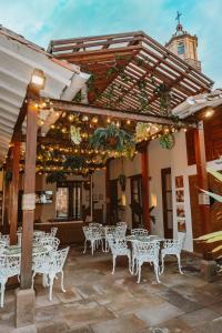 a patio with white tables and chairs under a pergola at HOTEL BOUTIQUE EL CAMPANARIO in San Gil