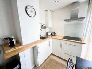 a kitchen with white cabinets and a clock on the wall at Appartement les Falaises in Cap d'Agde +2 photos
