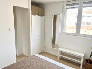a bedroom with white walls and a window and a mirror at Appartement les Falaises in Cap d'Agde