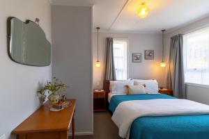 Un dormitorio con una cama azul y un espejo. en Cottage135-Rotorua, en Rotorua