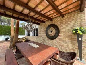 tavolo da pranzo e orologio su un muro di mattoni di Villa las palmeras bonita casa con piscina privada a Les tres Cales
